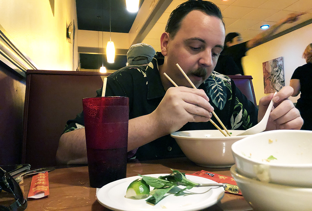Ben eating pho with chopsticks